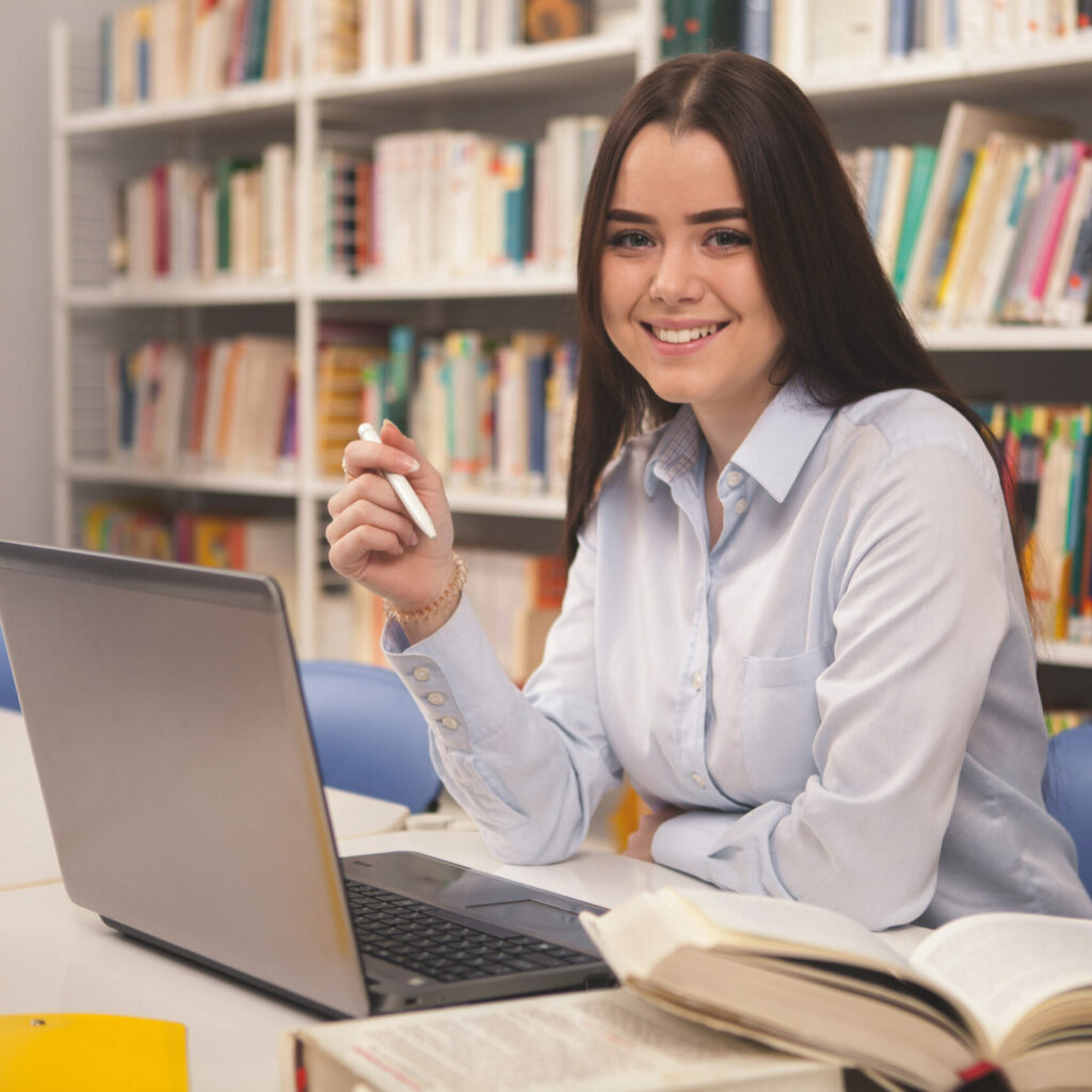 Lovely female student working on laptop at the library